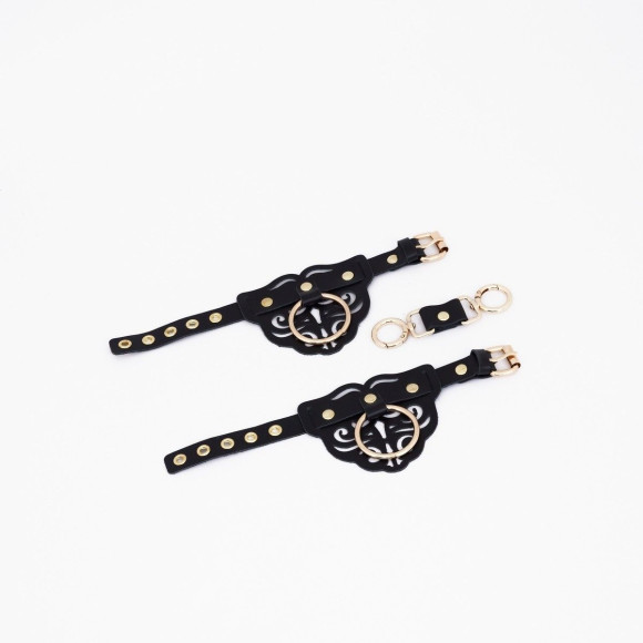 Черные кожаные наручники с клепками, кольцами и золотистой фурнитурой Черные кожаные наручники с клепками, кольцами и золотистой фурнитурой